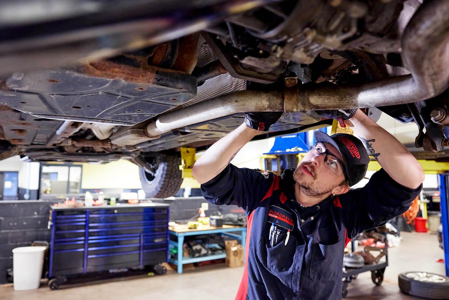 Auto technician student looking under a car.